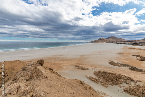 An idyllic beach at a remote location inside an arid landscape at Atacama Desert coast. The waves coming from the Pacific Ocean crash the rocks of the desert on an amazing wild dry scenery 