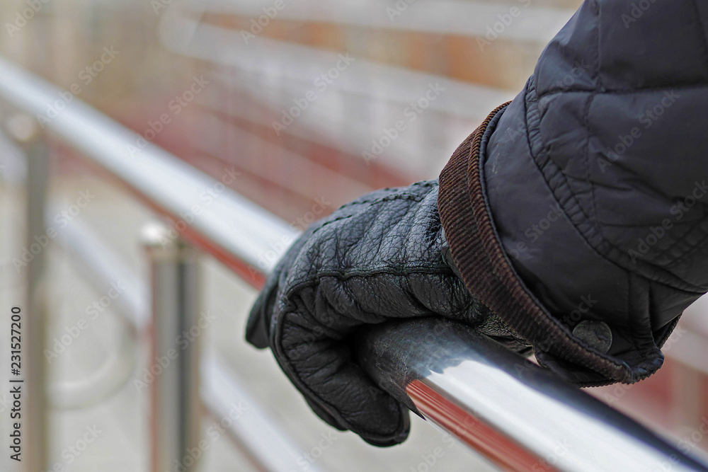 man's hand in glove holding handrail