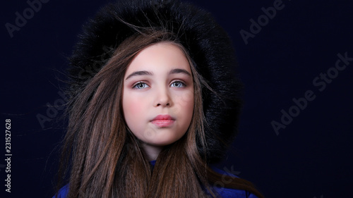 Портрет девушки зимой в теплой одежде с капюшоном, дует ветер