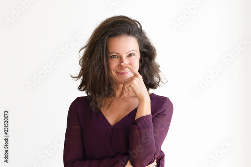 Happy thoughtful woman with finger on her nose. Beautiful Caucasian adult female with a smile expression on her face. Isolated on white. Thoughtful concept