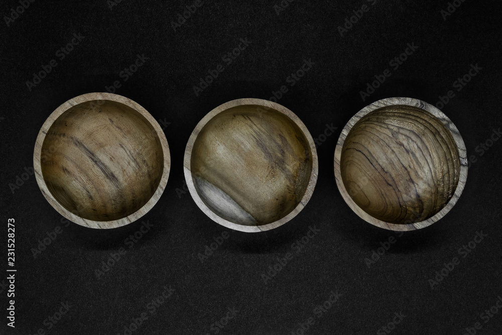 Three brown bowls made from palm tree wood placed in line on black background Three brown bowls made from palm tree wood placed in line on black background