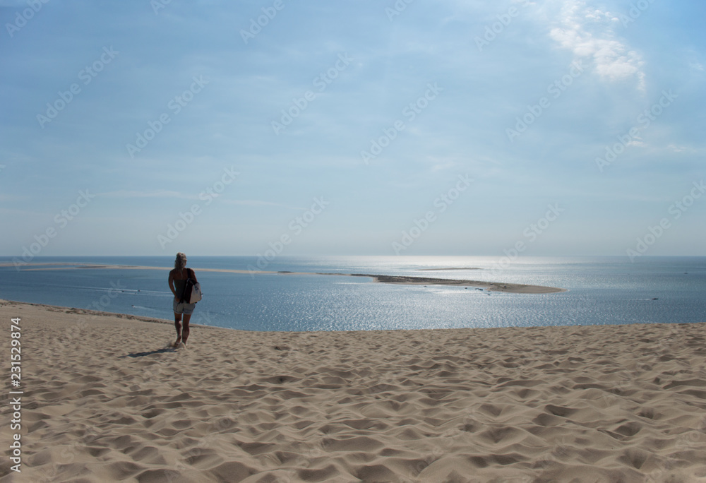 European woman walking in the sand of Dune de Pilat, France to the sea