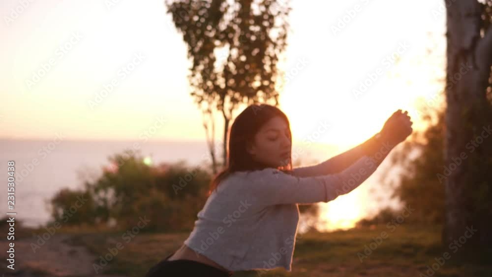 Active woman exercising and stretching in city park in front the sea or ocean. Attractive fit girl training squatting at morning outdoors. Healthy, fitness, wellness lifestyle Active woman exercising and stretching in city park in front the sea or ocean. Attractive fit girl training squatting at morning outdoors. Healthy, fitness, wellness lifestyle