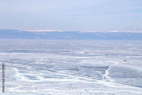 Cracks on the surface of the blue ice. Frozen lake in winter mountains. It is snowing. Lake Baikal. Winter © Elena Sistaliuk