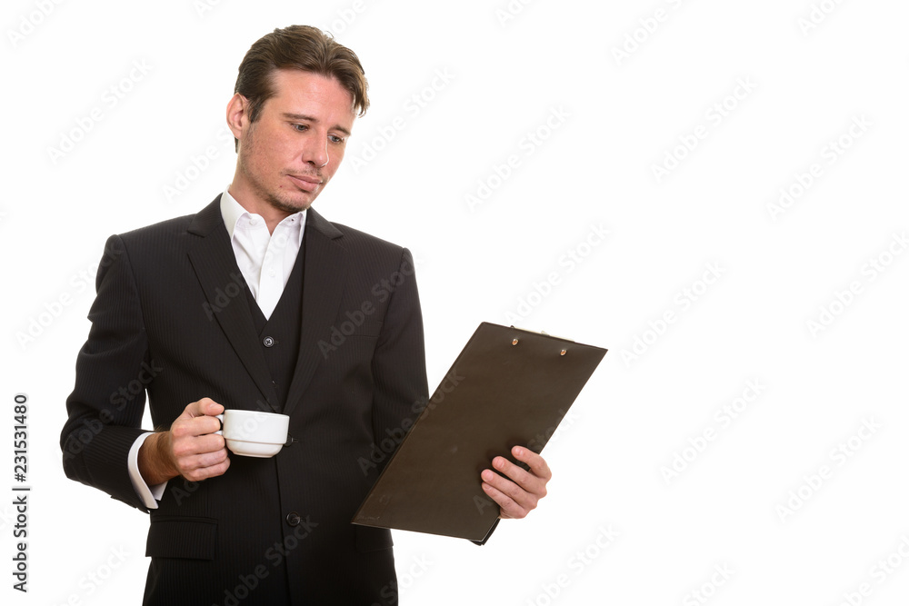 Handsome Caucasian businessman reading clipboard while holding c Handsome Caucasian businessman reading clipboard while holding c