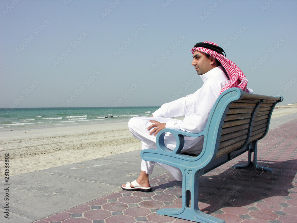arab man sitting on bench at the beach