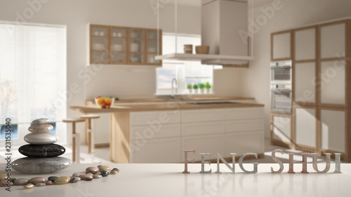 White table shelf with pebble balance and 3d letters making the word feng shui over wooden and white kitchen with island  stools and windows  zen concept interior design