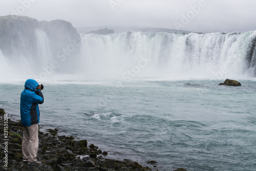 Photographer taking picture of Godafoss waterfall, Iceland photo