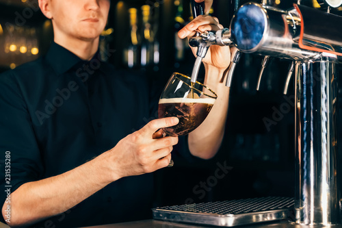 Hand of bartender pouring a large lager beer in tap in a restaurant or pub.