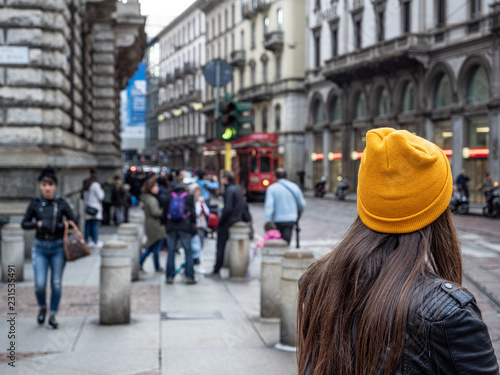 young tourist with yellow hat walks through the streets of downtown in winter. Milan, Italy