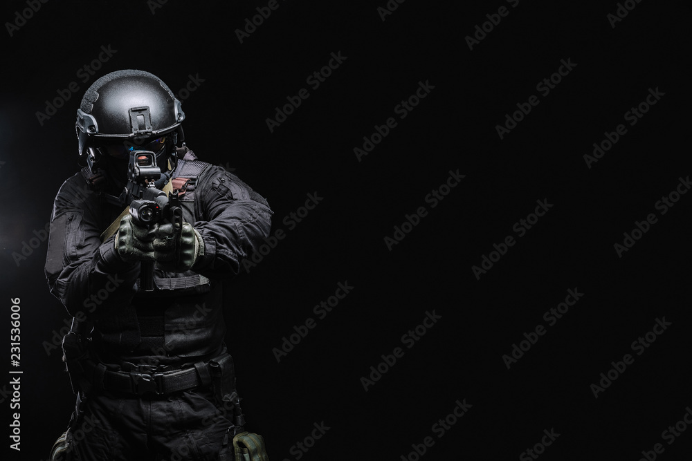 Airsoft player in an outfit with weapons on a black background Airsoft player in an outfit with weapons on a black background