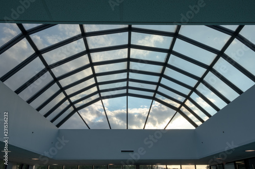 Modern glass roof with steel grid frames. Skylight rooftop window with symmetrical grid steel beams. Architectural detail and design on glass rooftop