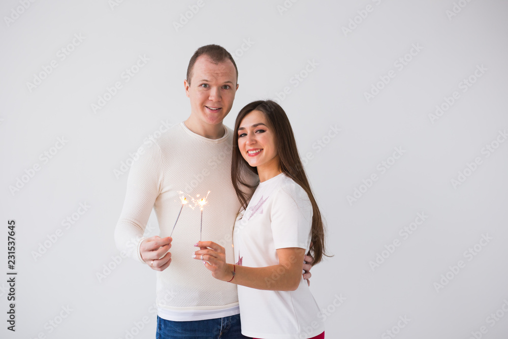Romantic beautiful couple having date at Valentine's Day. Man and woman holding sparklers on white background with copy space Romantic beautiful couple having date at Valentine's Day. Man and woman holding sparklers on white background with copy space