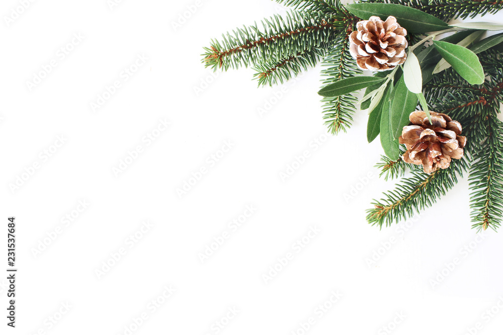 Christmas festive styled stock composition. Decorative corner. Pine cones, Fir and olive tree leaves and branches white wooden background. Flat lay, top view. Copy space.