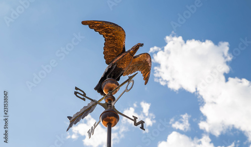 Fotografi Bronze Eagle as a weather vane on a rooftop.