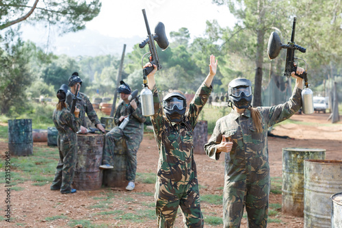 Cheerful young women in camouflage holding guns ready for playing paintball