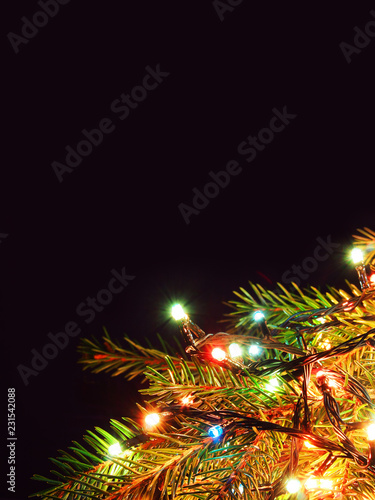 Christmas lights on Christmas tree, decorative garland isolated on dark background. New year close-up