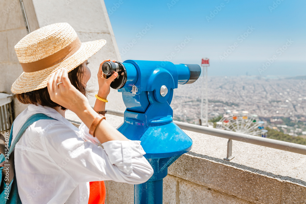 Happy woman sightseeing in city vacation using telescope viewer