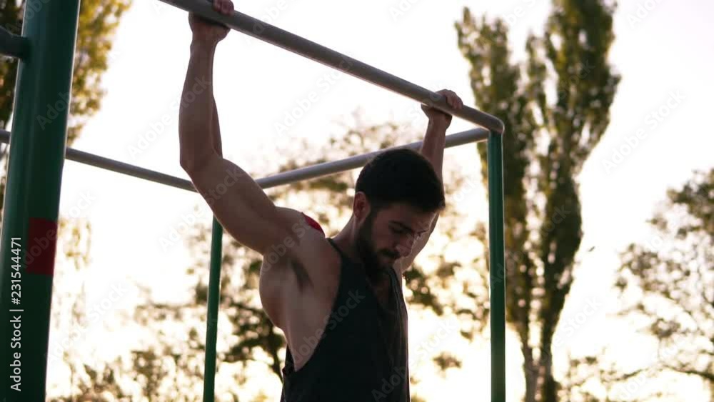 Pull-up strength training exercise - fitness man working out his arm muscles on outdoor gym doing chin-ups pull-ups as part of a crossfit workout work Pull-up strength training exercise - fitness man working out his arm muscles on outdoor gym doing chin-ups pull-ups as part of a crossfit workout work