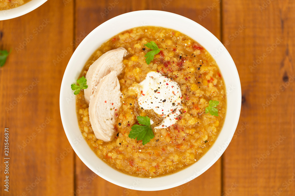 Turkish lentil bulgur soup sprinkled with pepper in a white bowl on a wooden background Turkish lentil bulgur soup sprinkled with pepper in a white bowl on a wooden background