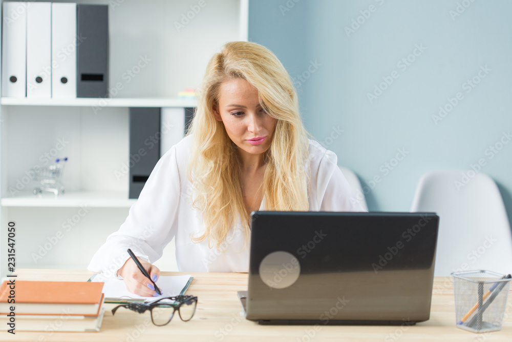 Technology, work and people concept - Beautiful blond woman sitting at her desk and working on laptop Technology, work and people concept - Beautiful blond woman sitting at her desk and working on laptop