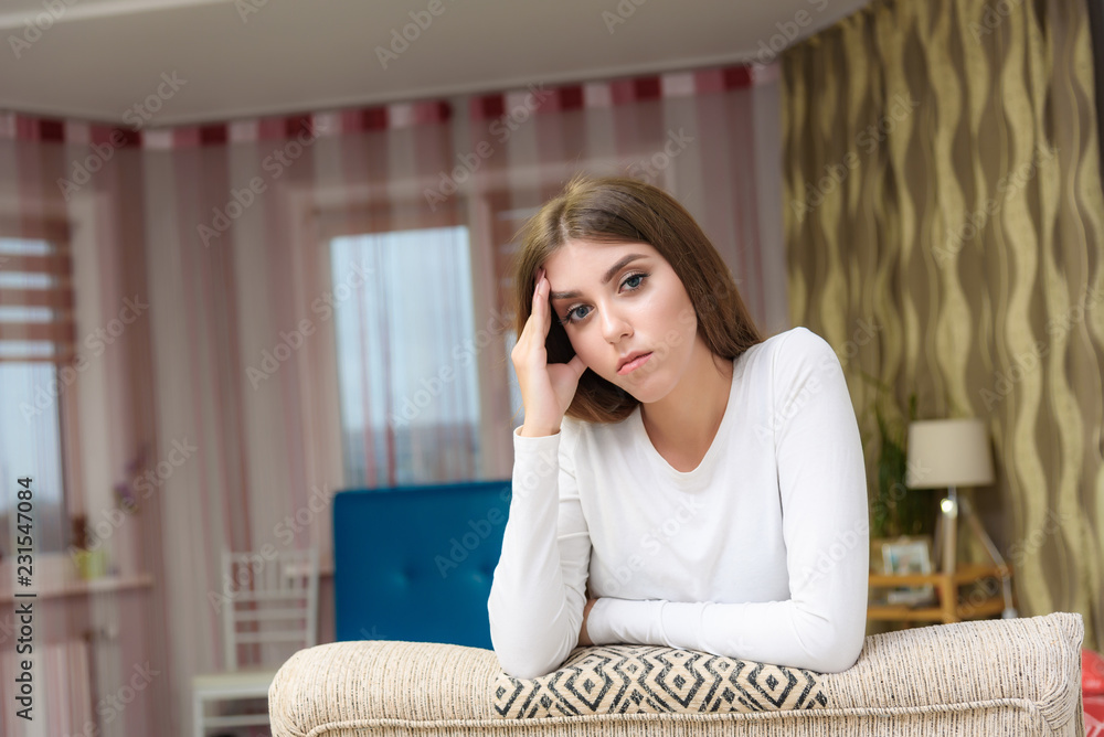 Portrait of a beautiful bored brunette girl in a room on the sofa. Portrait of a beautiful bored brunette girl in a room on the sofa.