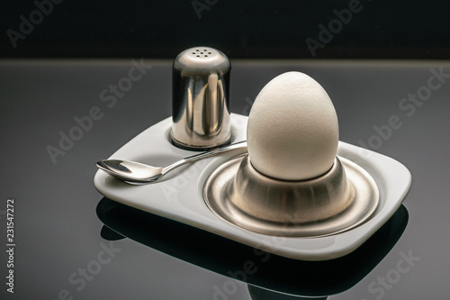 White boiled egg in a cup on a black background photo