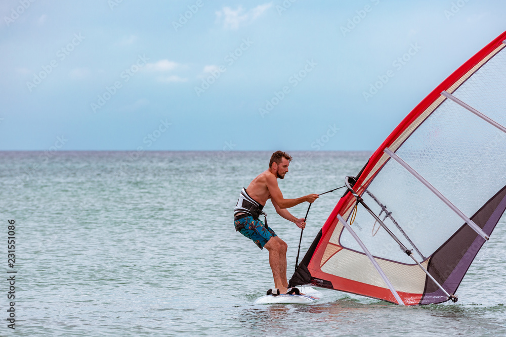 Naklejka premium Surfer riding waves in a beautiful sunny day. Young man enjoying the wind and the ocean surfing.