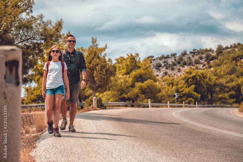 Obraz premium Father and daughter hiking on the mountain road