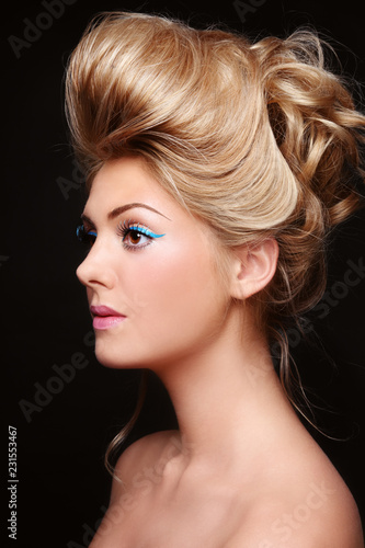 Young beautiful woman with fancy cat eye make-up and vintage style prom hairdo