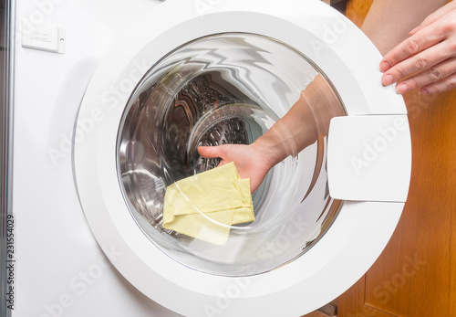 The girl washes with a cloth the glass washing machine.