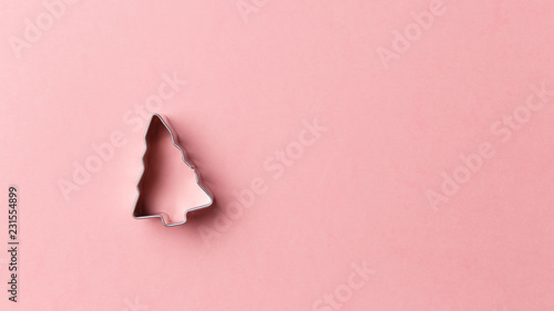 Christmas tree cookie cutter on pink background with copy space. Top view. Flat lay. Trendy colorful photo. Minimal style with colorful paper backdrop. Christmas concept