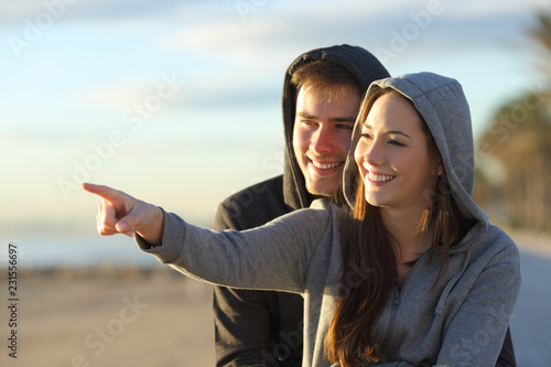Couple of happy teens pointing at horizon © Antonioguillem
