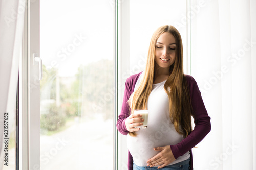 portrait of young pregnant woman in front of window. Girl drinking vegetable milk Free Download portrait of young pregnant woman in front of window. Girl drinking vegetable milk - GFXLoad