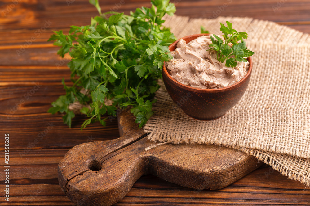 Homemade chicken liver pate with parsley in clay bowl