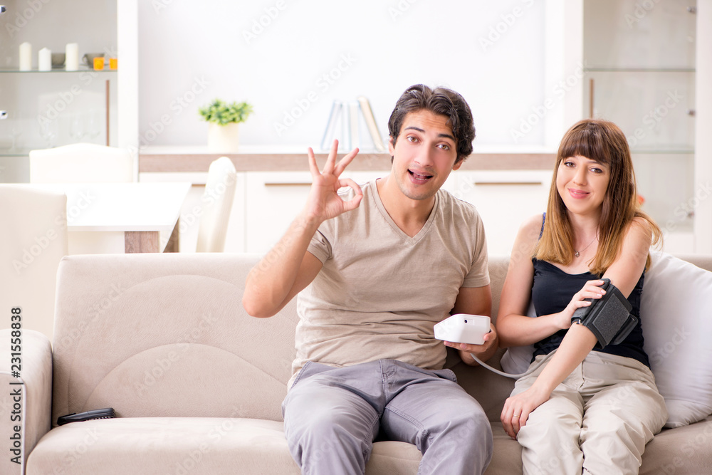 Husband checking wife's blood pressure