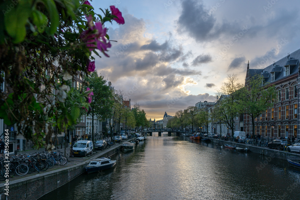 Fototapeta premium Kanał Amsterdamu przed zachodem słońca, dramatyczne niebo
