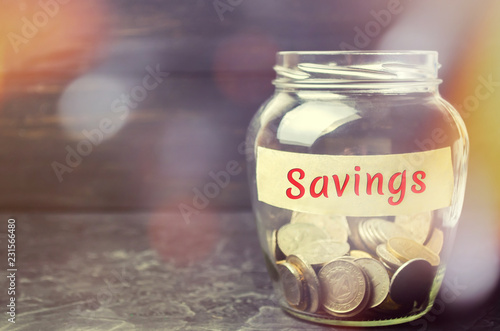 Glass jar with coins and the inscription "Savings". The concept of accumulating money in the family budget. Family Insurance. Distribution of cash savings. Saving retirement money Pension