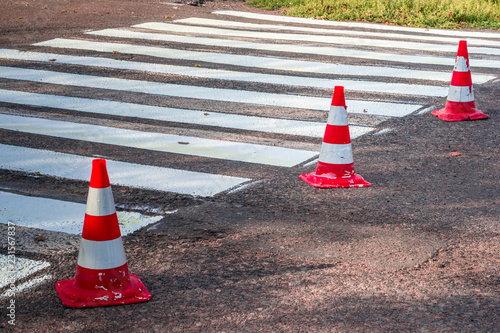 Road cones signal with two reflective stripes on the road with a pedestrian crossing photo