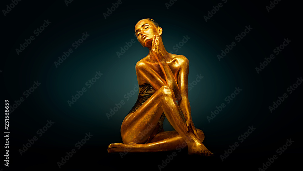 Fototapeta premium Wysokiej mody modela dziewczyna z jaskrawym złotym błyska na jej ciele pozuje, pełny długość portret piękna seksowna kobieta z rozjarzoną ciało skórą. Makijaż projektowy