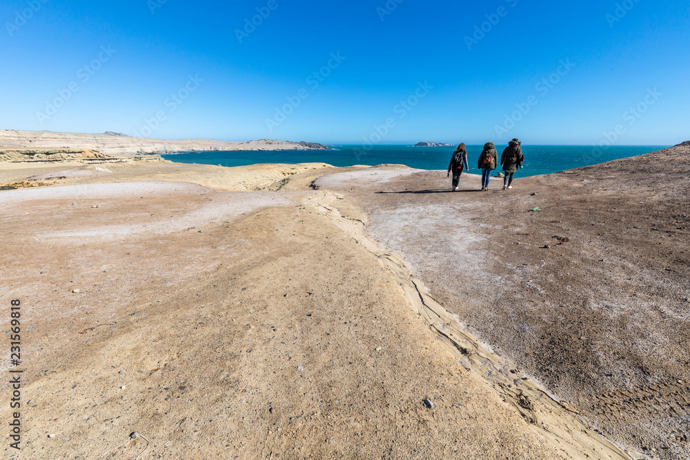 Three people walking at Atacama Desert in a cliff walk along Chorrillos. A nice walk along the cliffs with amazing views over the Pacific Ocean
