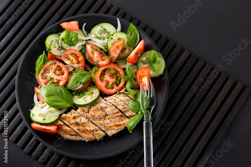 Vegetable salad and grilled chicken on a black background. Healthy food. Diet.