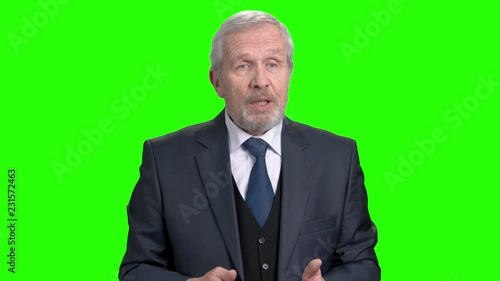 Elderly businessman talking and gesturing with hand. Senior business man talking during presentation and using hand gestures, chroma key background.