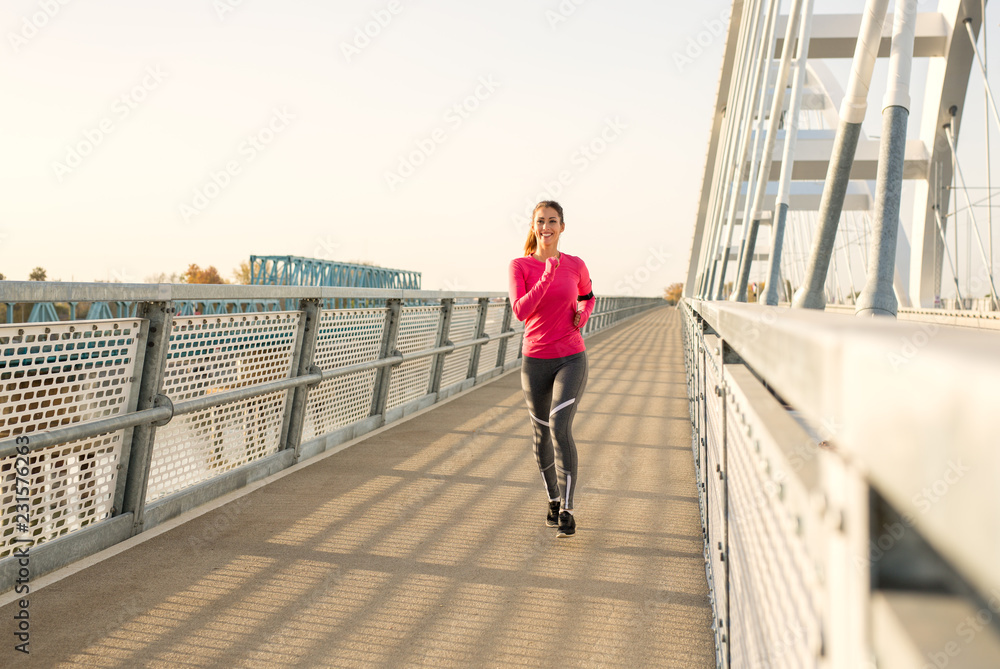 Beautiful young fit woman running  on a bridge doing her workout
