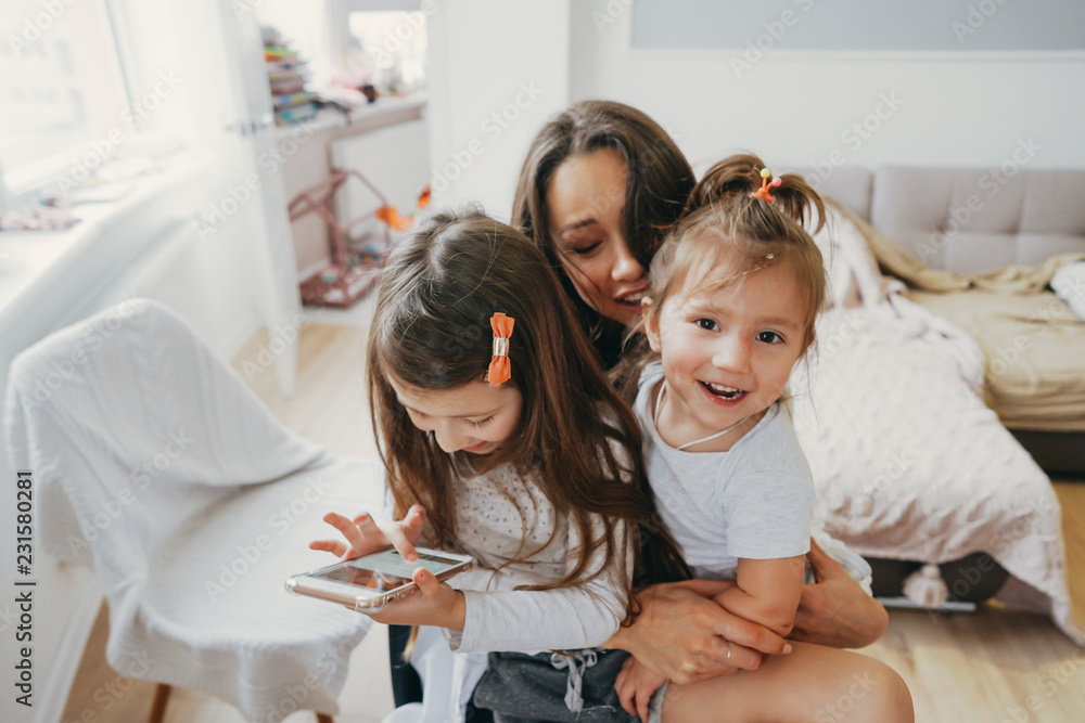 Mom and two daughters are looking at the smartphone Mom and two daughters are looking at the smartphone