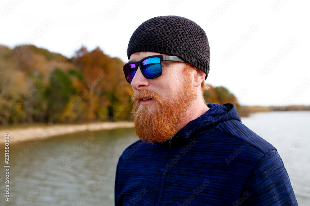 Redheaded man standing on bridge over lake Redheaded man standing on bridge over lake