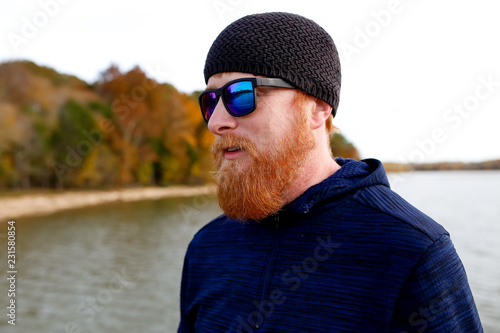 Redheaded man standing on bridge over lake