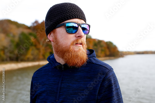 Redheaded man standing on bridge over lake