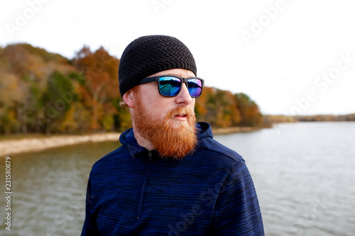 Redheaded man standing on bridge over lake