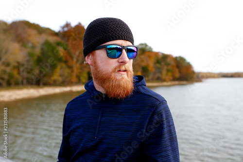 Redheaded man standing on bridge over lake